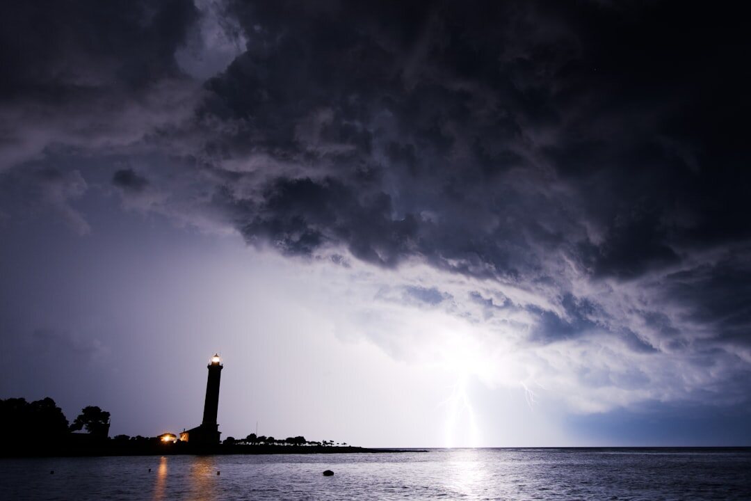 Adriatic coastal lighthouse at dusk under a dramatic stormy sky