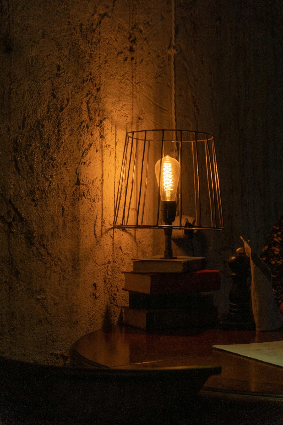 Stack of old leather-bound books lit by warm lamplight on a wooden desk