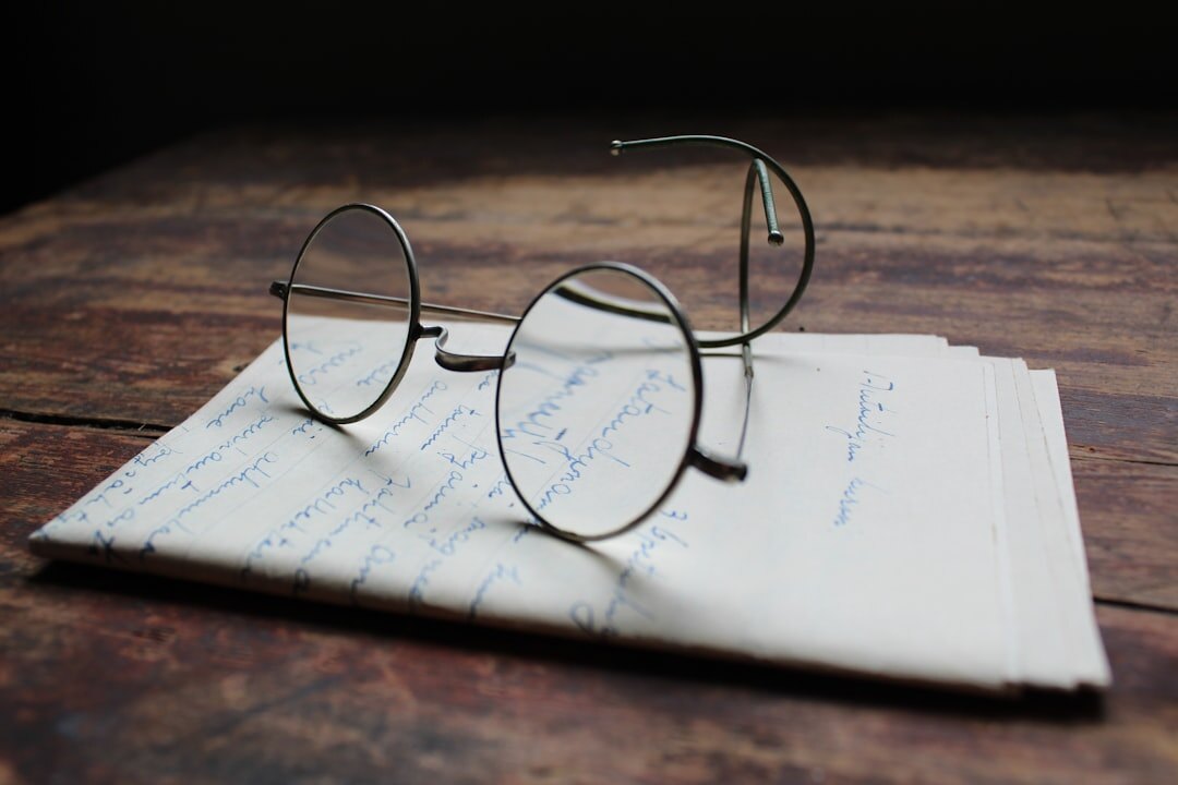 Open handwritten notebook with an old city map and reading glasses on a wooden table