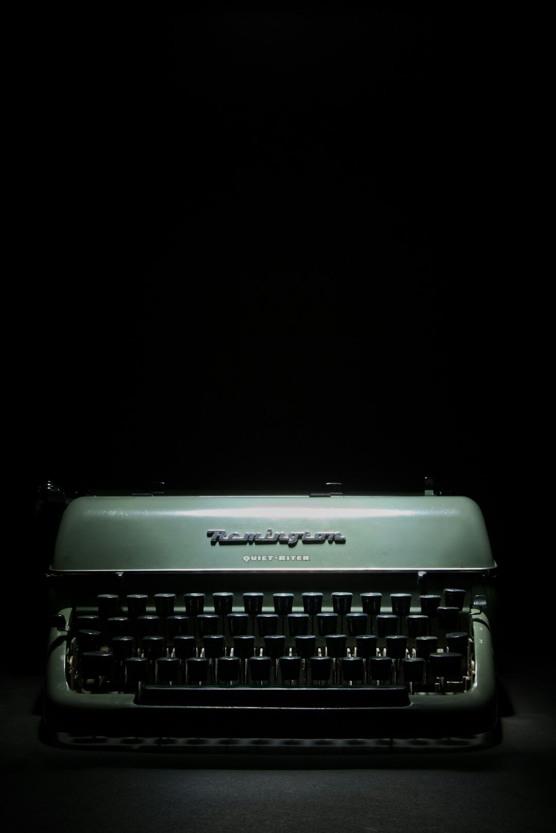 Vintage typewriter on a wooden desk at night with dramatic side lighting