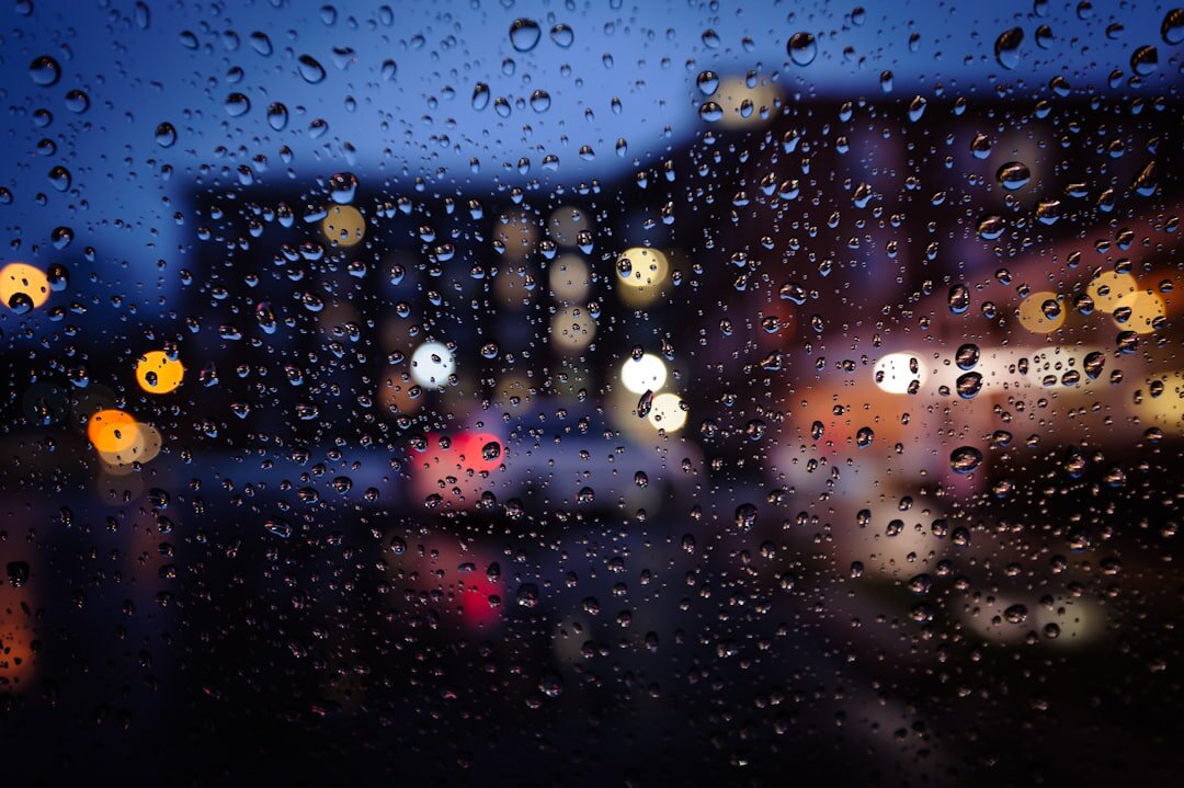 Raindrops on a window with blurred city lights in the background at night