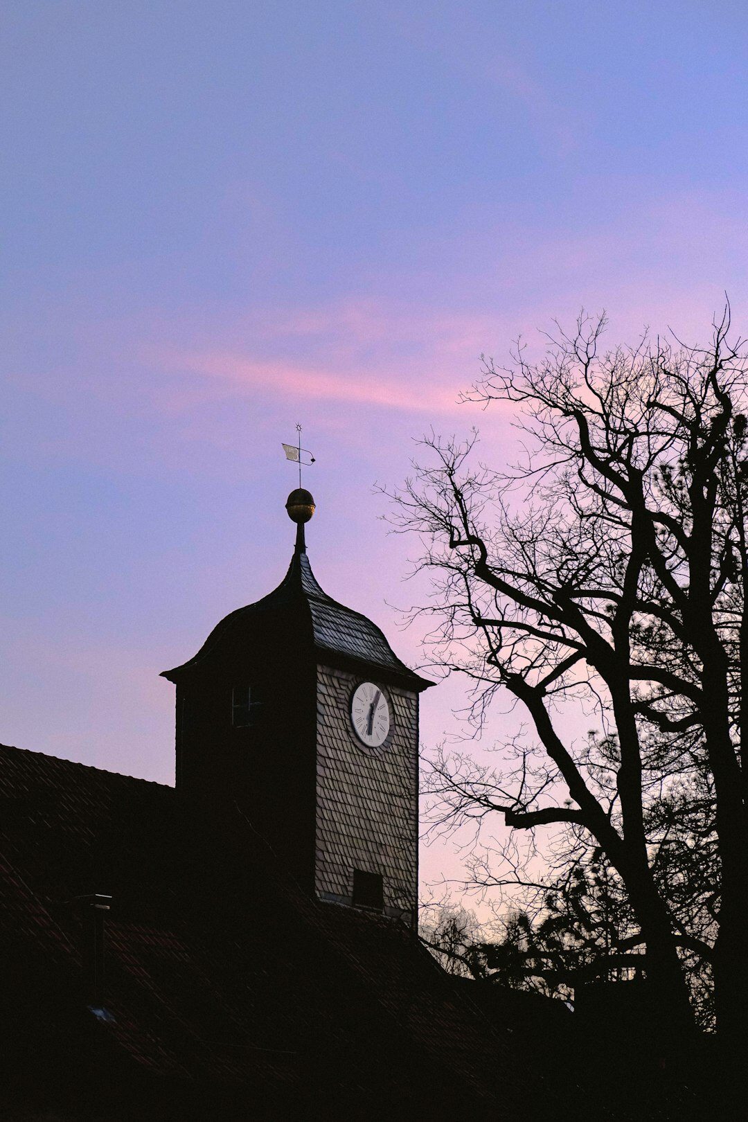 Old stone clock tower silhouetted against a dramatic dusk sky