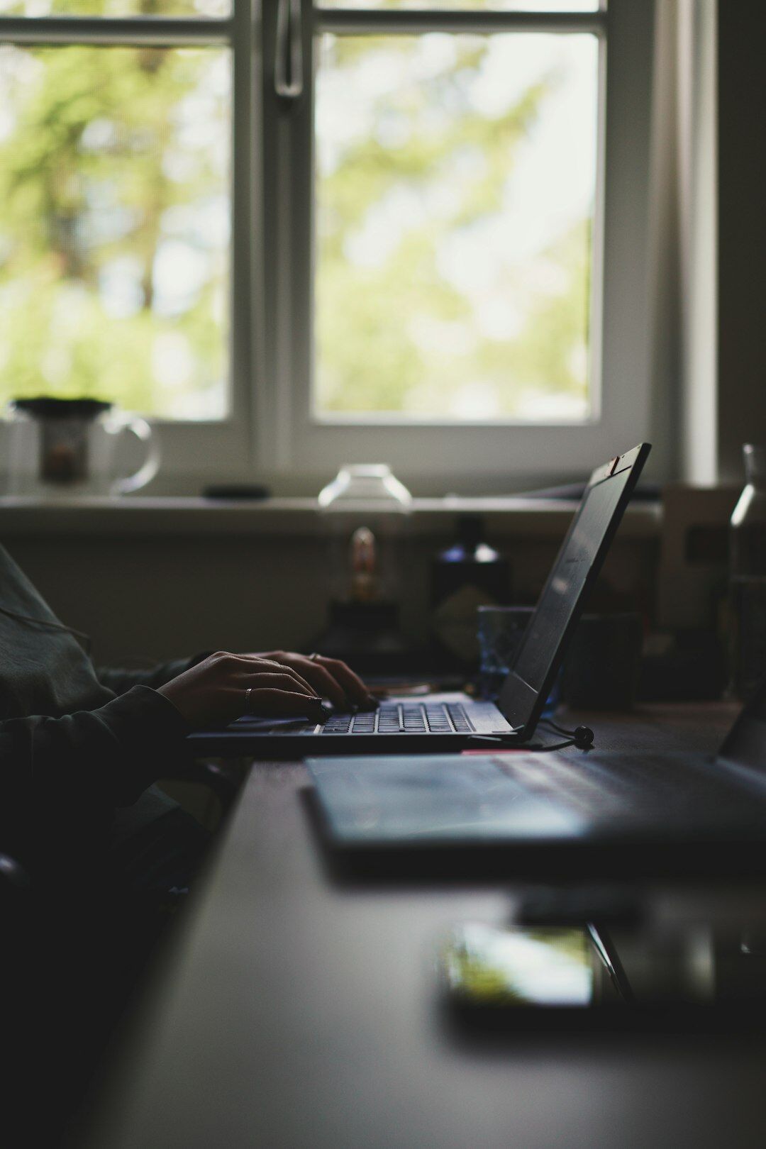 person writing in notebook by window